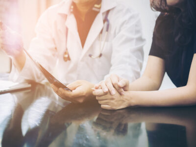 Doctor and patient consulting on a table Doctor and patient consulting on a table about women health. Medical concept. Selective focus at patient's hands.